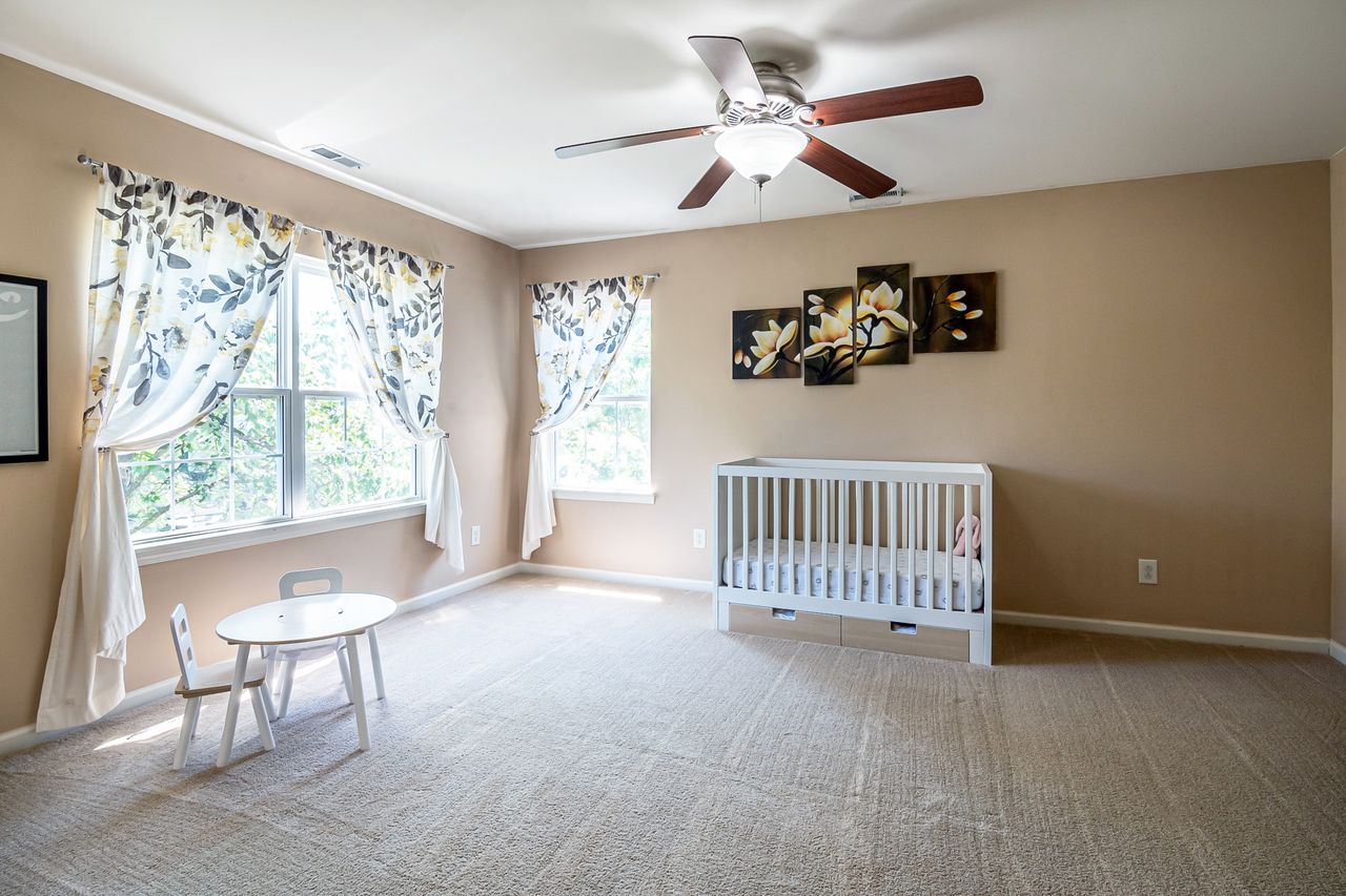Crafting Captivating Headlines: Your awesome post title goes here A spacious nursery room with a crib, white table and chair set, and floral curtains under natural light.